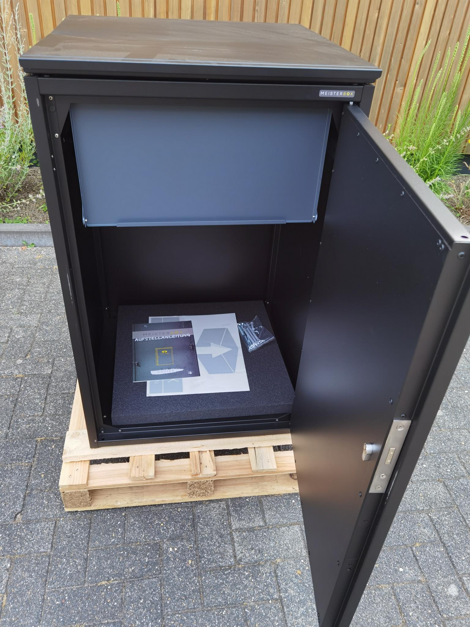 Die Abb. zeigt den Paketkasten Kaster M in Tiefschwarz mit geöffneter Tür.
